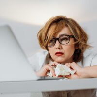 女性起業家が本音の悩みを抱えながらノートパソコンに向かって考え込んでいる様子