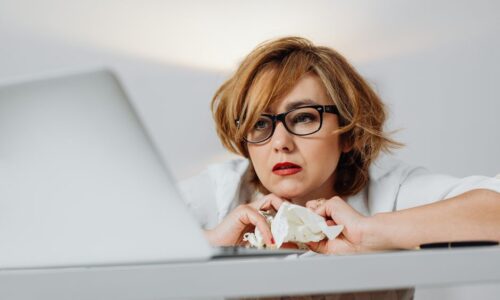 女性起業家が本音の悩みを抱えながらノートパソコンに向かって考え込んでいる様子