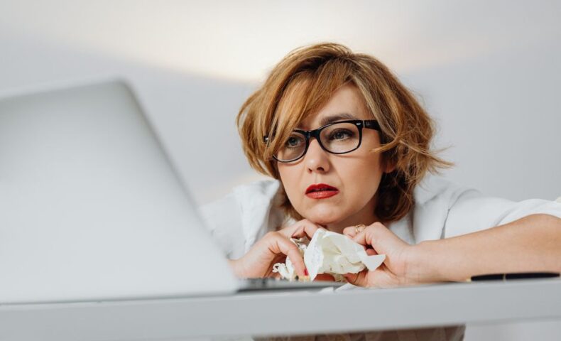 女性起業家が本音の悩みを抱えながらノートパソコンに向かって考え込んでいる様子