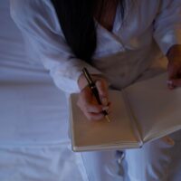 起業前夜に不安を抱えながらメモを書く女性の手元 - 起業の不安解消のイメージ
